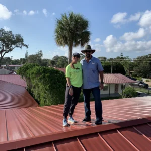 Two people standing on a red roof.