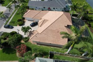 Aerial view of a house with a tan tiled roof and surrounding greenery.