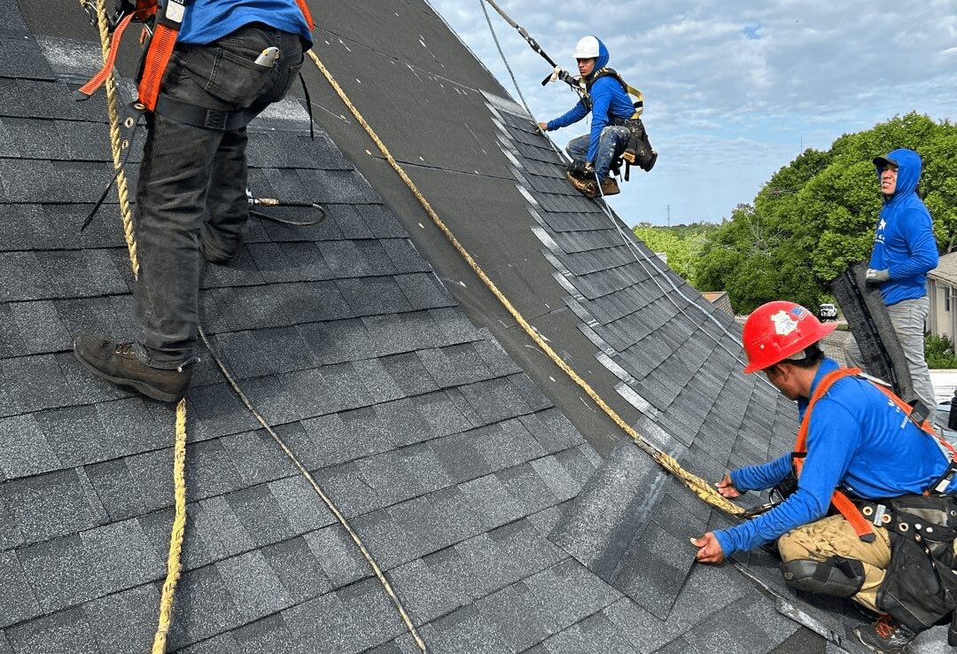 roofers installing a new shingle roofconstruction worker seated on wooden trusses